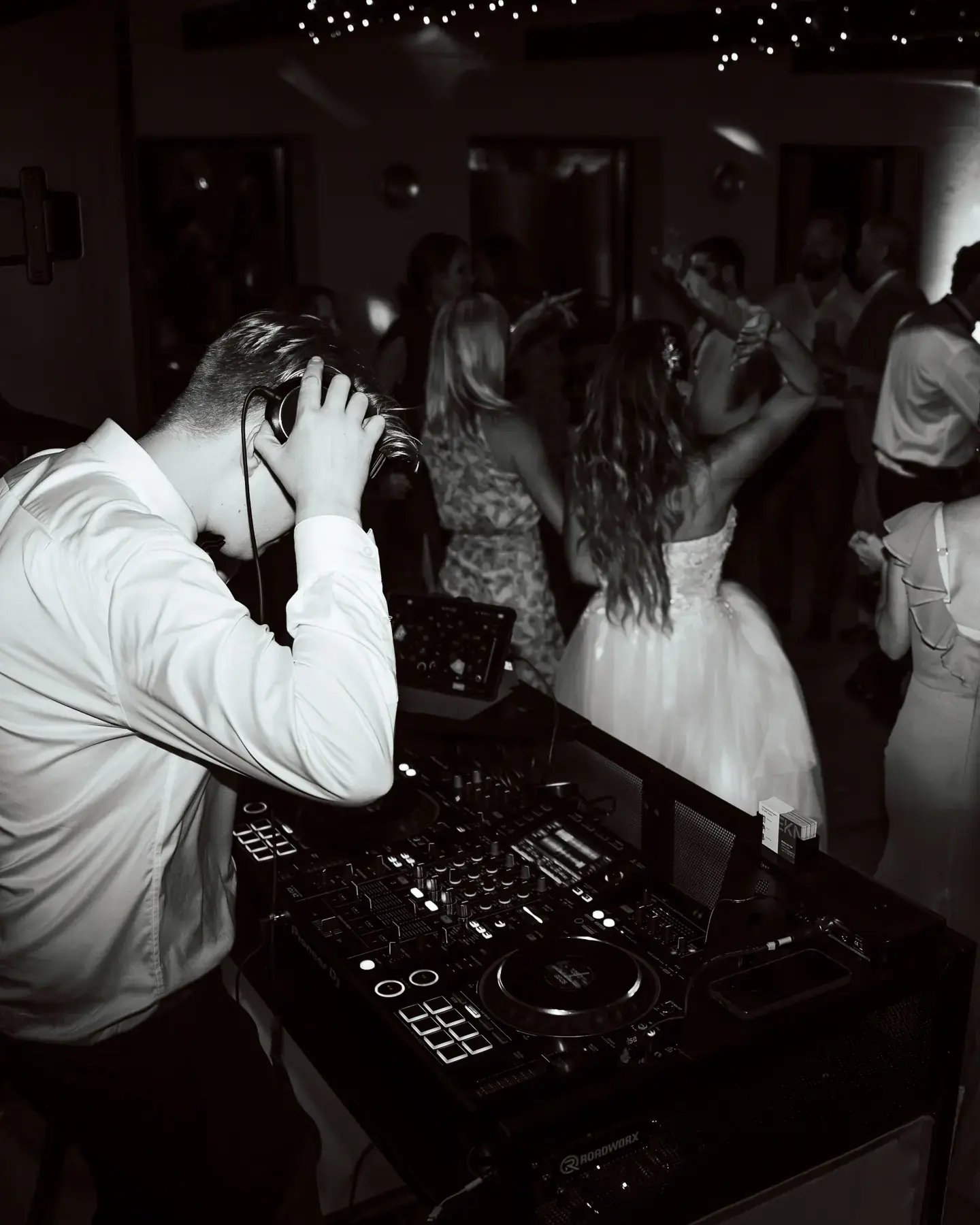 Bröllopsgäster dansar under fest med DJ och belysning